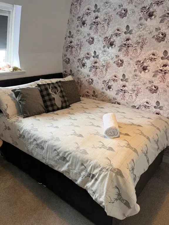 a bed in a bedroom with a floral wall at THE KEMPS 7bed 6 bathroom PARKING for 3 vehicles Ideal for contractors Next to LIDLE part of Langleycottageandapartments portfolio REDUCTION FOR LONG STAYS in Inverness