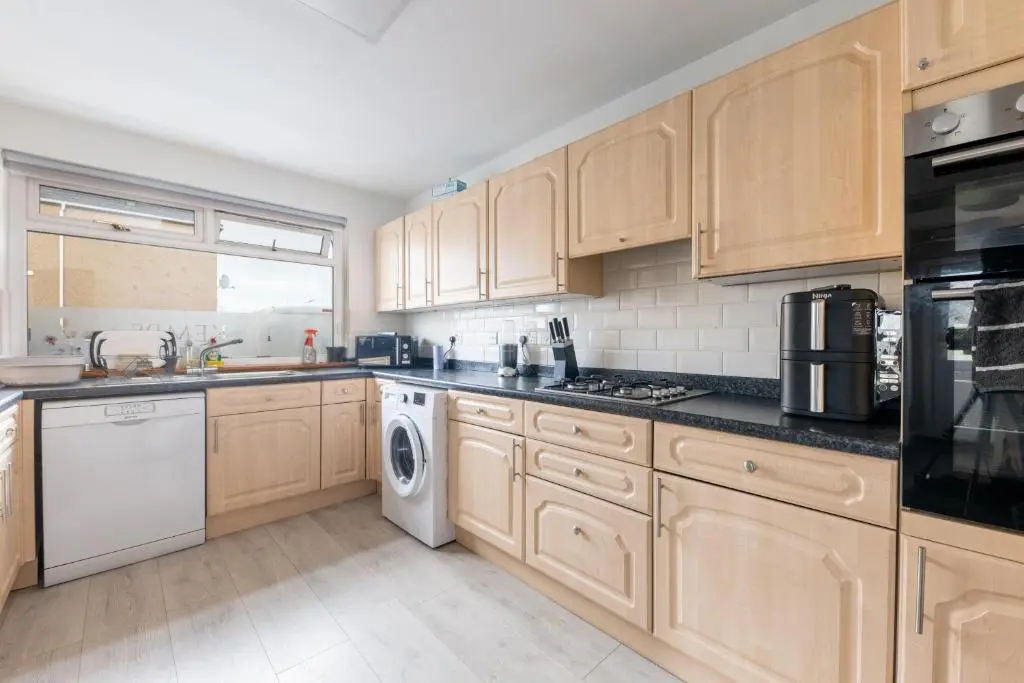 a kitchen with wooden cabinets and a washer and dryer at THE KEMPS 7bed 6 bathroom PARKING for 3 vehicles Ideal for contractors Next to LIDLE part of Langleycottageandapartments portfolio REDUCTION FOR LONG STAYS in Inverness