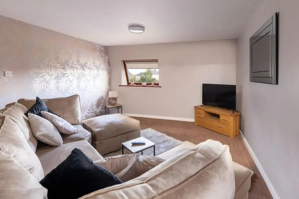 a living room with a couch and a television at THE KEMPS 7bed 6 bathroom PARKING for 3 vehicles Ideal for contractors Next to LIDLE part of Langleycottageandapartments portfolio REDUCTION FOR LONG STAYS in Inverness