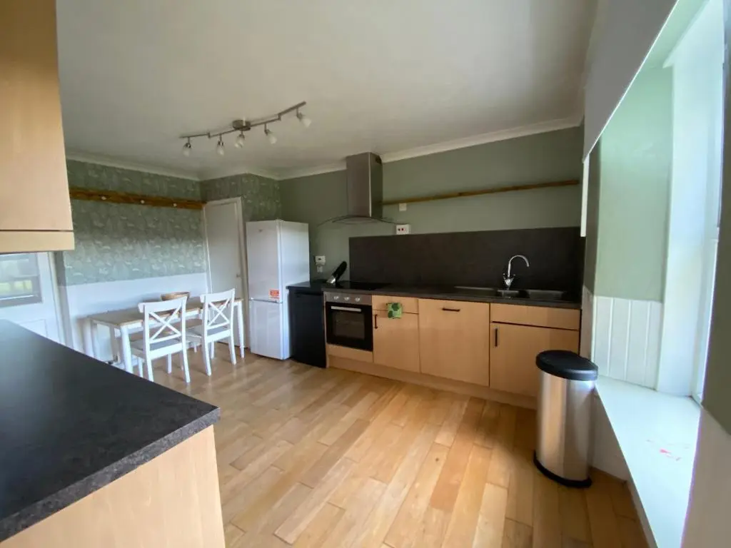 a kitchen with black countertops and a kitchen with a table at Struan Cottage in Knockandhu