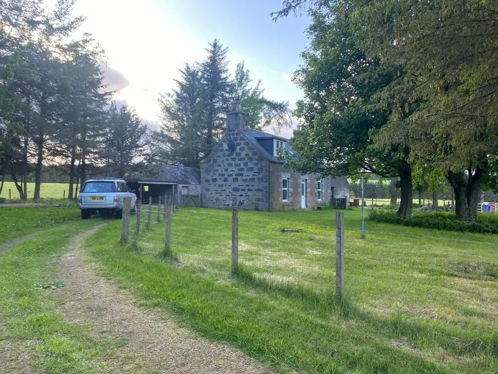 a truck parked in front of a stone house at Struan Cottage in Knockandhu