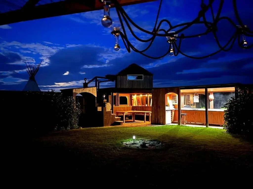 a house with a lit up yard at night at Private Speyside Tipi Retreat and Whisky Marrying Tun Hot Tub in Coltfield