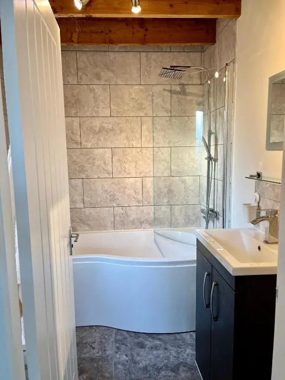 a bathroom with a white tub and a sink at House By The Sea in Portsoy