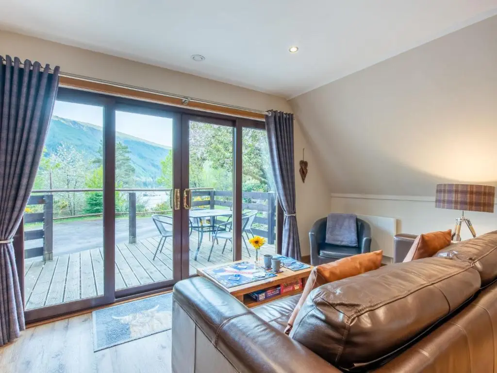 a living room with a leather couch and a balcony at Chalet Heron Lodge by Interhome in Spean Bridge