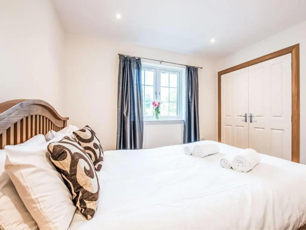 a bedroom with a white bed with pillows and a window at Holiday Home Mountain View Lodge by Interhome in Whitebridge