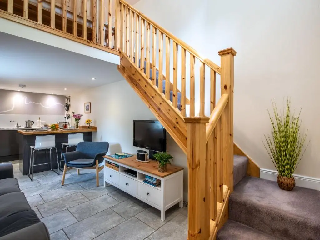 a living room with a staircase with a couch and a television at Holiday Home Betty's Bothy by Interhome in Drumnadrochit