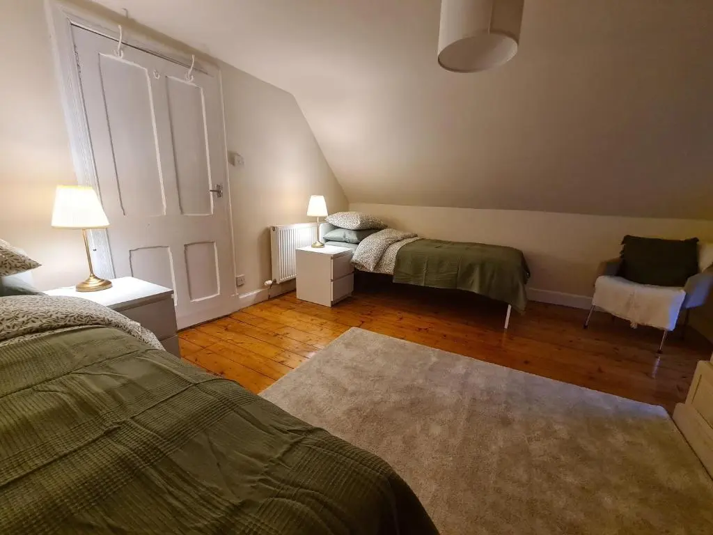 a bedroom with two beds and a chair and a door at Alltachbeg in Tomintoul