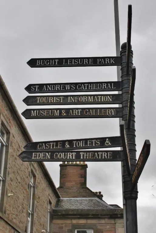 a group of signs on a pole in front of a building at Modern ground floor flat, Inverness city in Inverness