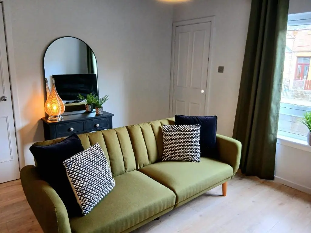 a living room with a green couch and a mirror at Modern ground floor flat, Inverness city in Inverness