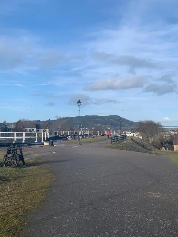 an empty road with a white fence and a bridge at Modern ground floor flat, Inverness city in Inverness