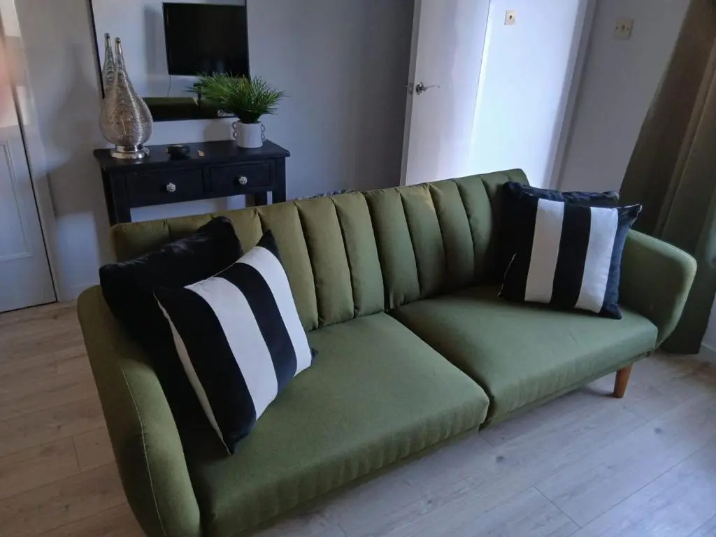 a green couch with pillows on it in a living room at Modern ground floor flat, Inverness city in Inverness
