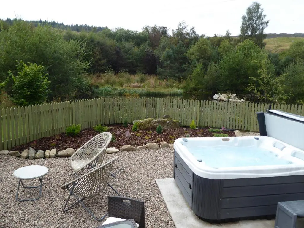 a hot tub in a yard with a table and chairs at Shepherds View in Glenshee