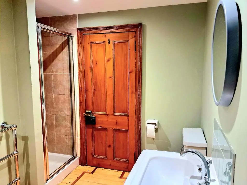 a bathroom with a wooden door and a white sink at Apartment 42b by the river in Inverness