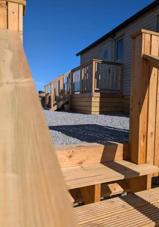 a row of wooden benches in front of a building at Shephards Hut by the Beach in Findhorn
