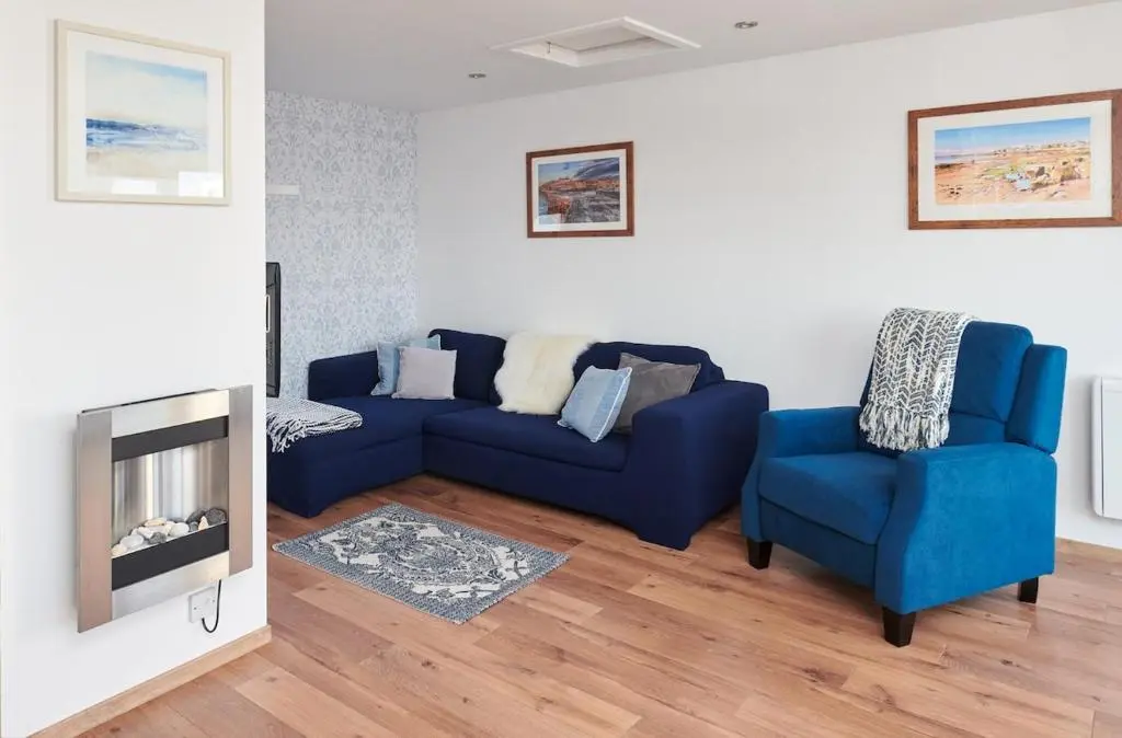 a living room with a blue couch and two chairs at The Sandpiper in Burghead