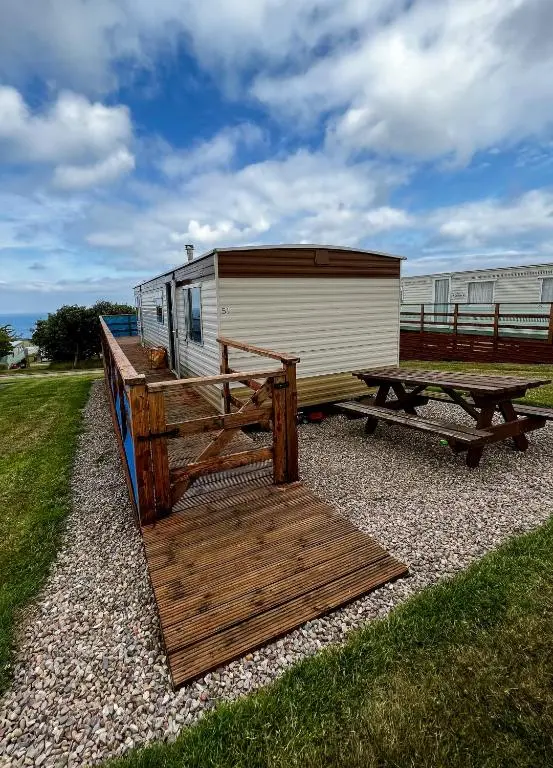 a trailer with a wooden deck and a picnic table at Caravan Nr 51 Only for Family Holiday