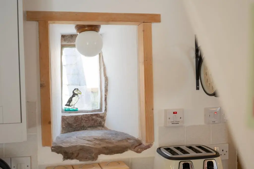 a kitchen with a window with a dog sitting in it at Seabreeze Cottage, 17 Seatown, Gardenstown in Gardenstown