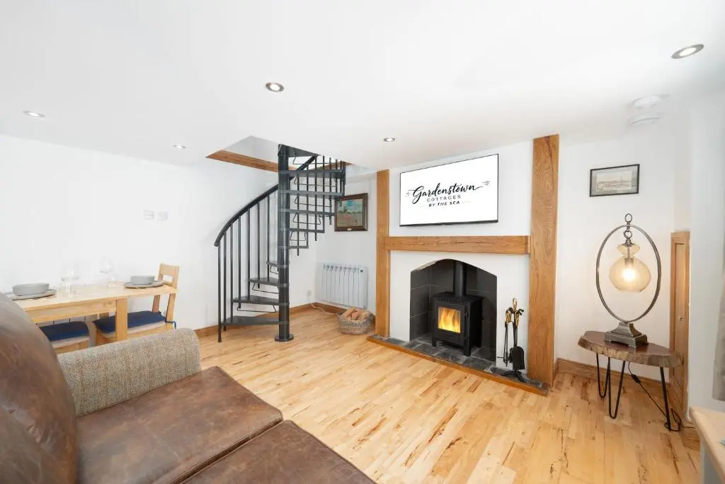 a living room with a fireplace and a staircase at Nautical Nook, 16 Seatown, Gardenstown in Gardenstown