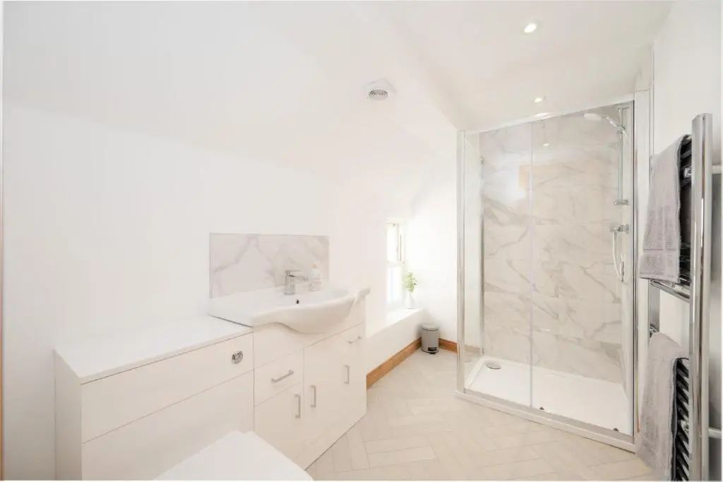 a white bathroom with a sink and a shower at Nautical Nook, 16 Seatown, Gardenstown in Gardenstown
