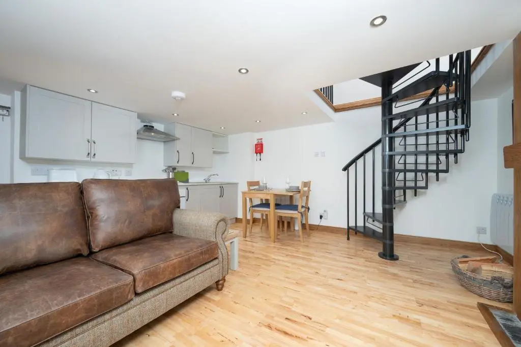 a living room with a couch and a kitchen at Nautical Nook, 16 Seatown, Gardenstown in Gardenstown
