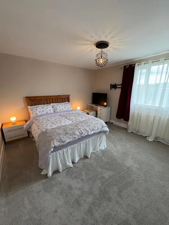 a bedroom with a large bed and a chandelier at Apartment in Inverness in Inshes