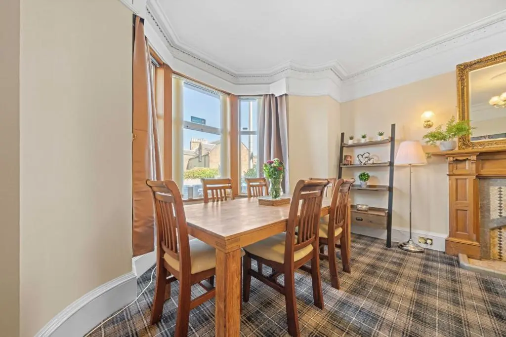 a dining room with a wooden table and chairs at mySTAYINN Cedar Villa 9 Bedroom House - Inverness in Inverness