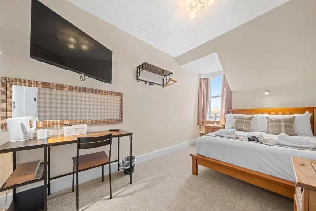 a bedroom with a bed with a desk and a tv at mySTAYINN Cedar Villa 9 Bedroom House - Inverness in Inverness