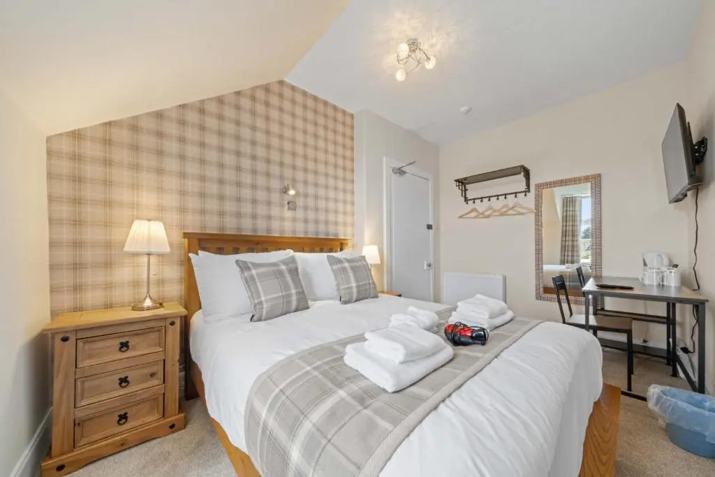 a bedroom with a large bed with towels on it at mySTAYINN Cedar Villa 9 Bedroom House - Inverness in Inverness