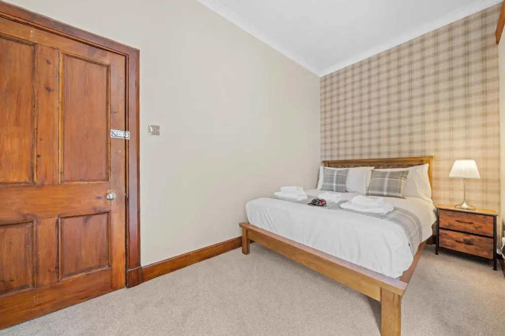a bedroom with a bed and a wooden door at mySTAYINN Cedar Villa Guest House in Inverness