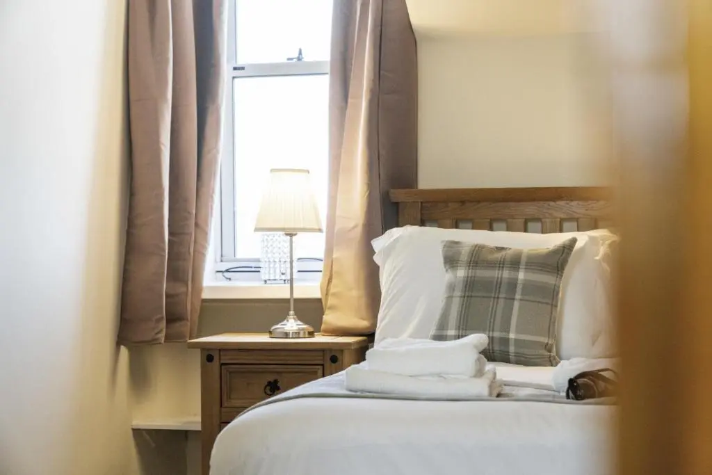 a bedroom with a bed with towels on it at mySTAYINN Cedar Villa Guest House in Inverness