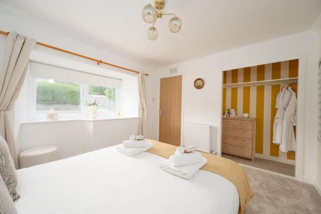 a bedroom with a large white bed and a window at Hideaway Cottage W Hot Tub in Portsoy
