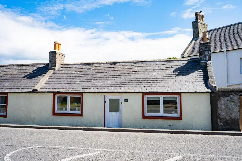 a white house with a grey roof and red windows at Hideaway Cottage W Hot Tub in Portsoy