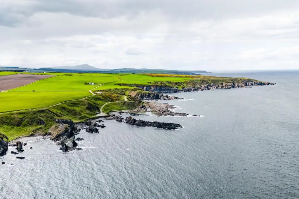 an aerial view of a golf course next to the ocean at Hideaway Cottage W Hot Tub in Portsoy