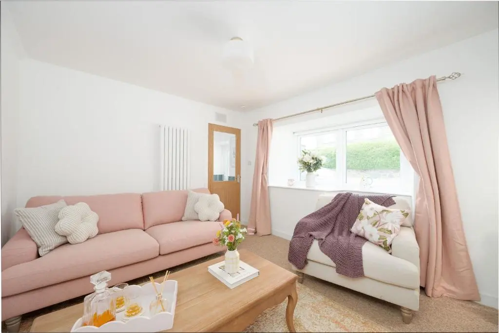 a living room with a pink couch and a table at Hideaway Cottage W Hot Tub in Portsoy