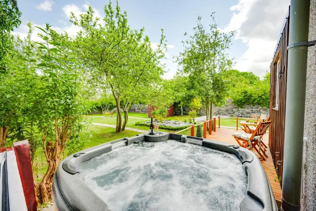 a hot tub in a yard with trees at The Garden Cottage with Hot Tub in Portsoy