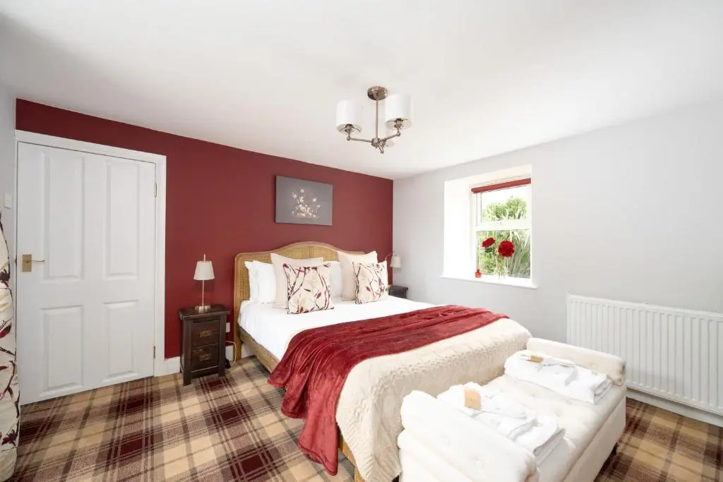 a bedroom with a bed with a red wall at The Garden Cottage with Hot Tub in Portsoy