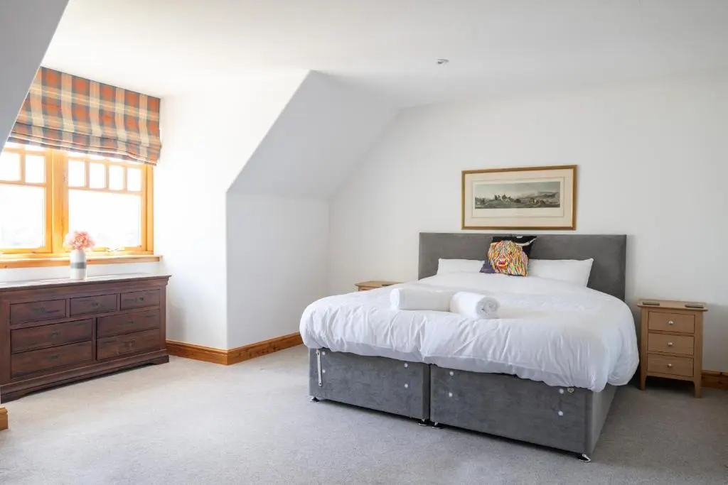 a bedroom with a large bed and a window at Old Distillery Lodge in Kingussie