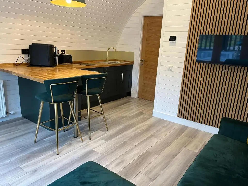 a kitchen with a counter and stools in a room at Rosevalley luxury Glamping grouse pods in Cawdor