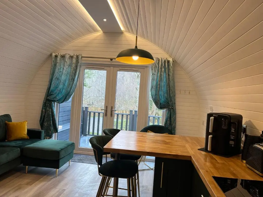 a living room with a table and chairs and a balcony at Rosevalley luxury Glamping grouse pods in Cawdor
