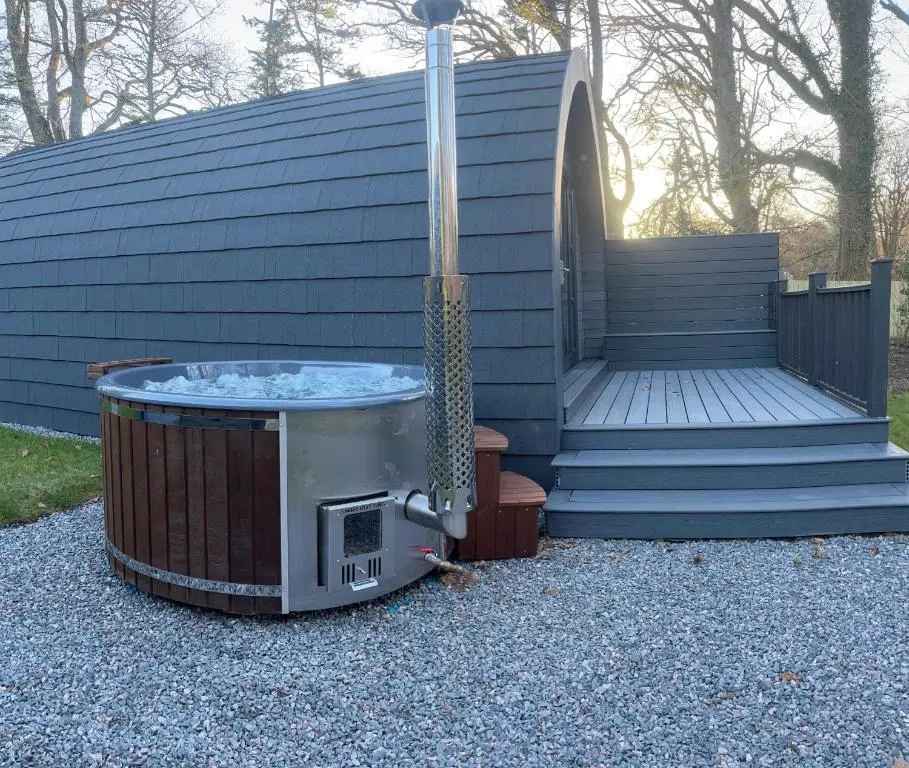a hot tub sitting in front of a house at Rosevalley luxury Glamping grouse pods in Cawdor
