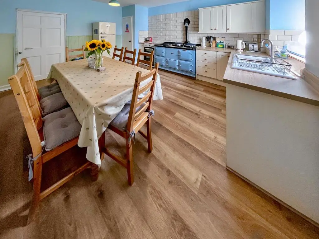 a kitchen with a table and chairs and a kitchen with blue cabinets at Rottal Farmhouse in Millton of Clova