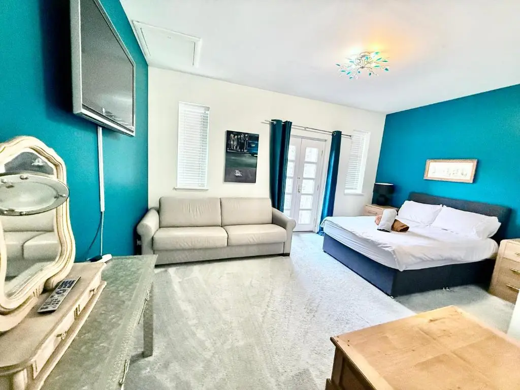 a bedroom with blue walls and a bed and a couch at Spacious Iconic Lesmurdie House 2 bed, free WiFi and Parking in Elgin
