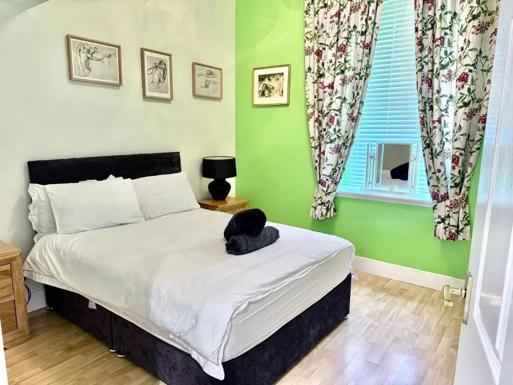 a bedroom with a bed with a black cat sitting on it at Spacious Iconic Lesmurdie House 2 bed, free WiFi and Parking in Elgin