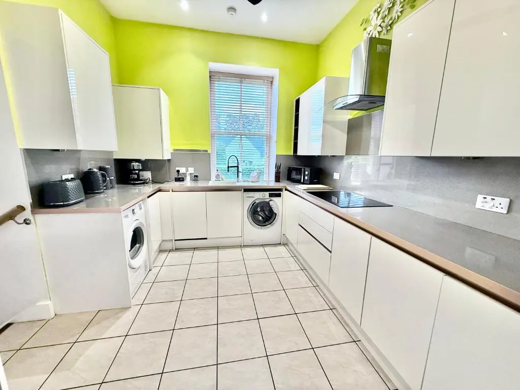 a kitchen with white cabinets and a washer and dryer at Spacious Iconic Lesmurdie House 2 bed, free WiFi and Parking in Elgin