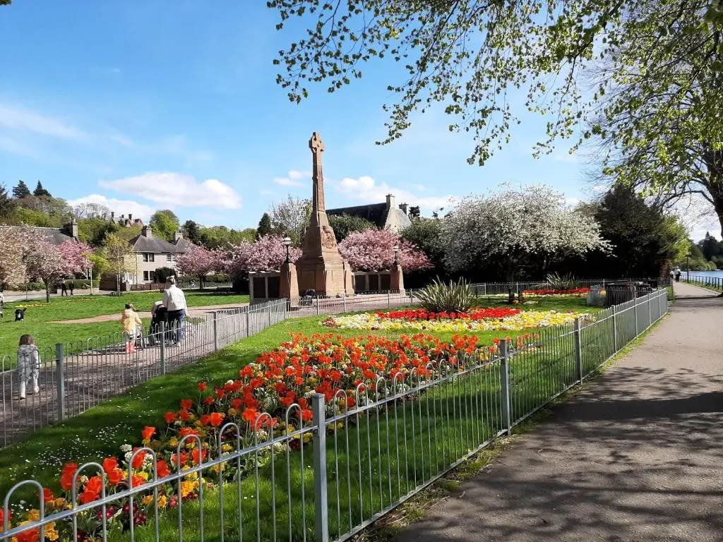a park with flowers and a statue in the background at Failte Stay in Inverness