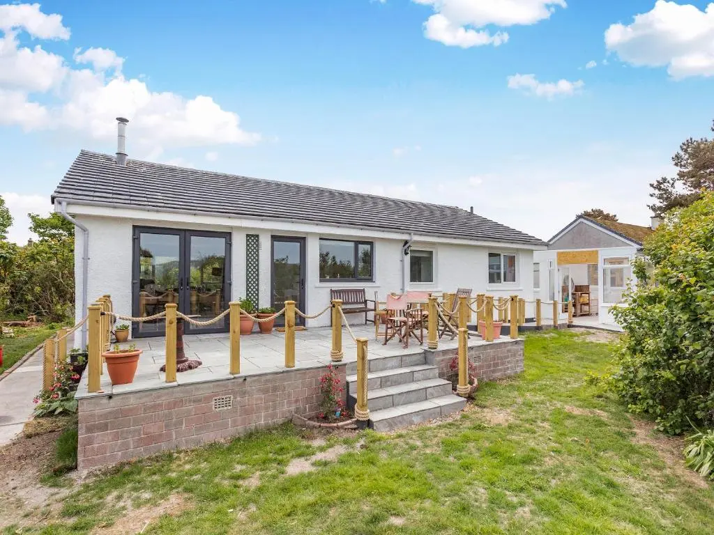 a house with a deck with a table and chairs at Highland Sanctuary in Dornoch