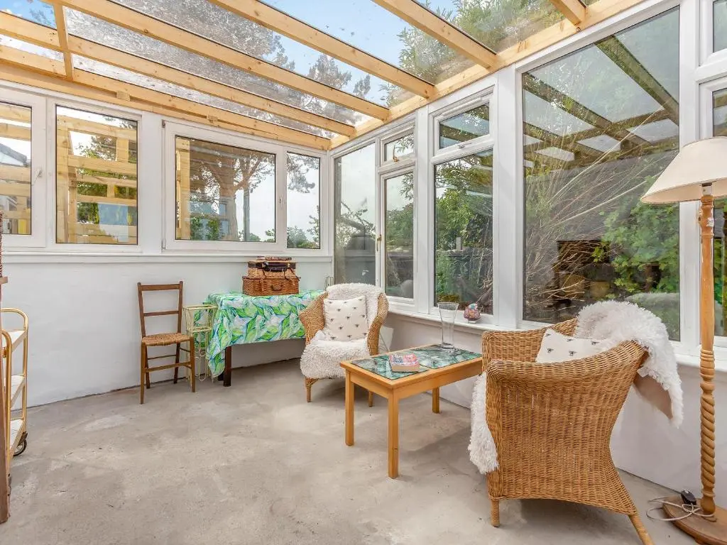 a conservatory with windows and a table and chairs at Highland Sanctuary in Dornoch