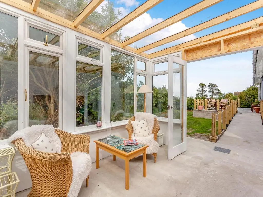 a conservatory with chairs and a table and windows at Highland Sanctuary in Dornoch