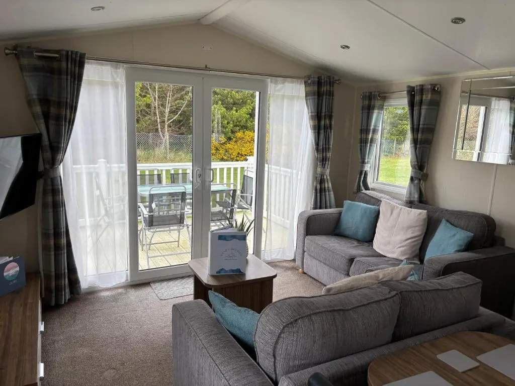 a living room with a couch and chairs and a patio at Sandy Shores in Embo