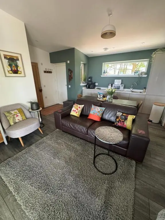 a living room with a brown leather couch at Wellhouse Country Lodges and Hot Tubs in Tore